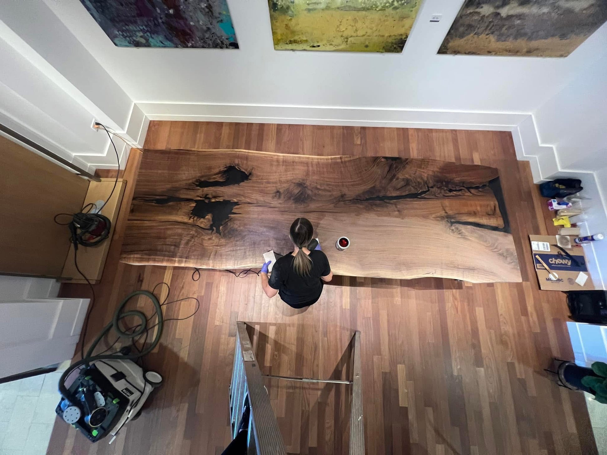 Person working on a large wooden slab in a workshop setting