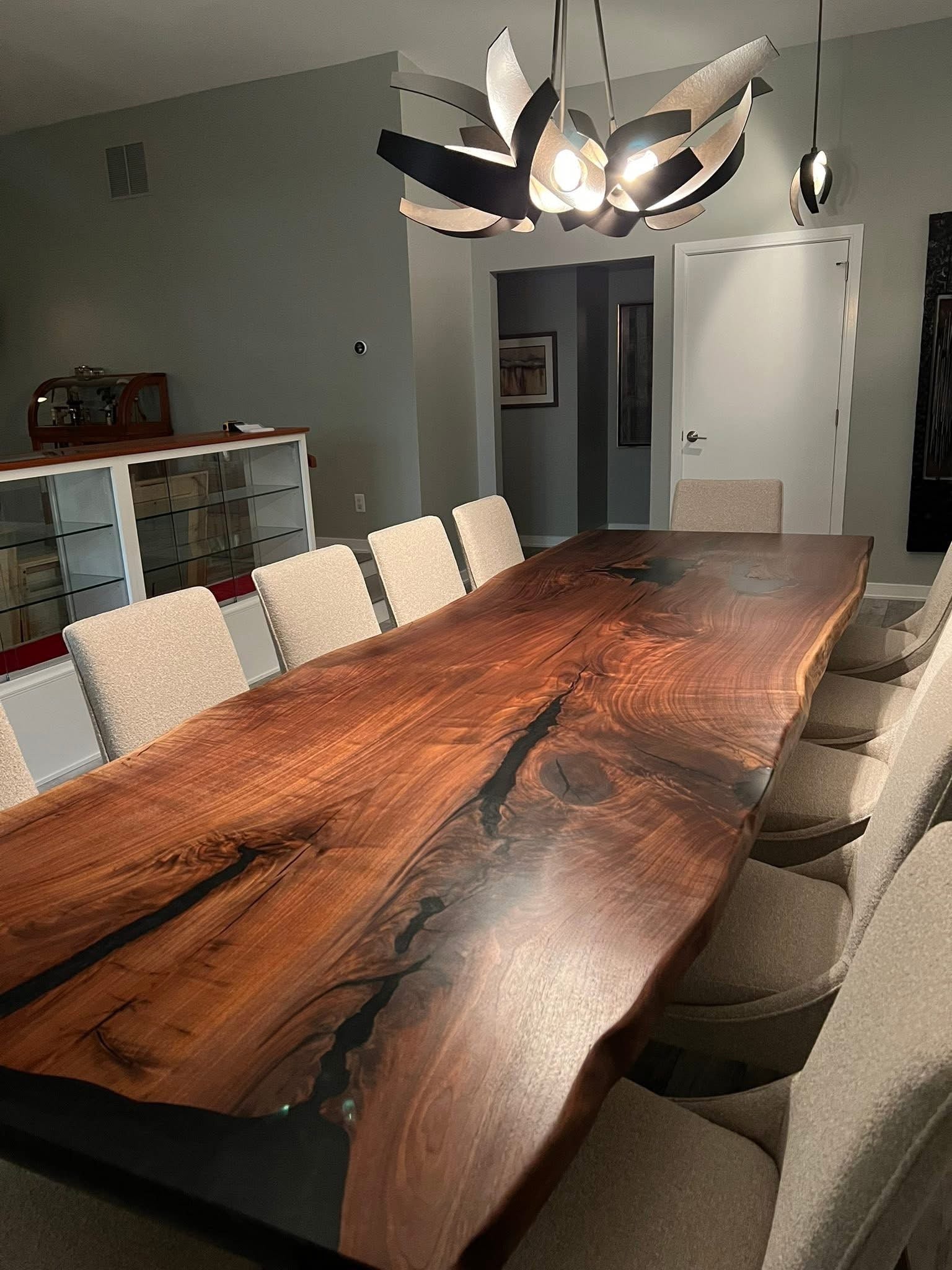 Dining room with a large wooden table and modern chairs, featuring a unique ceiling light fixture.